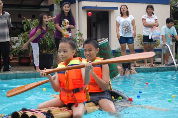 Peserta water games berusaha mengumpulkan bola warna-warni sambil menjaga keseimbangan di atas rakit di kolam renang Villa Giri Kembang