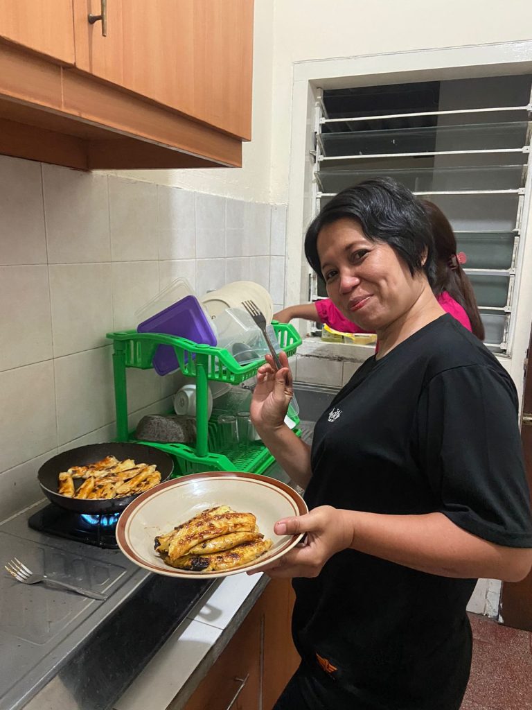 Ibu Mulyanah, tamu keluarga Villa Giri Kembang, sedang menikmati kegiatan memasak bersama di dapur Villa Menur dengan suasana hangat dan nyaman layaknya di rumah sendiri.